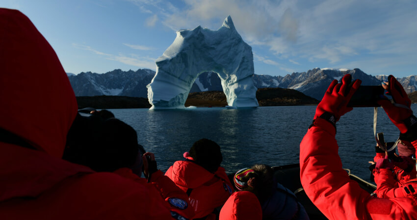 Пассажиры Зодиака фотографируют арочный айсберг