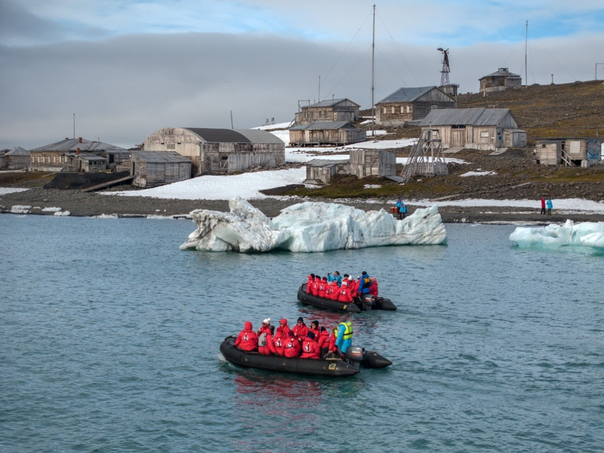 Туристы на лодках у берега поселения Арктики