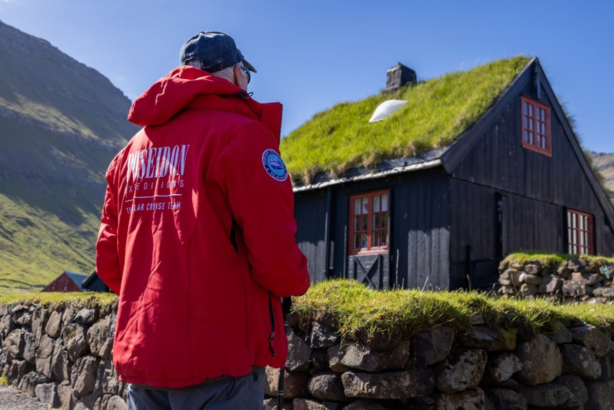 Турист рядом с дом с дерновой крышей