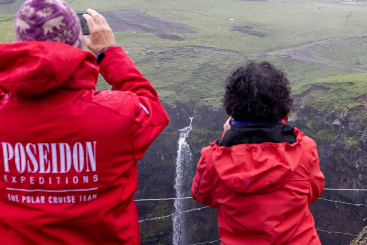 Туристы наблюдают за водопадом в скале